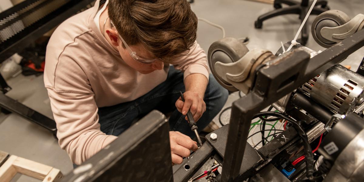 Mechanical Engineering student fixing a machine with a screwdriver