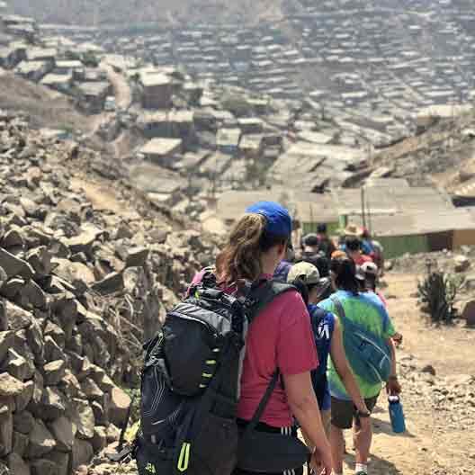 Students descend a hill to a refugee camp