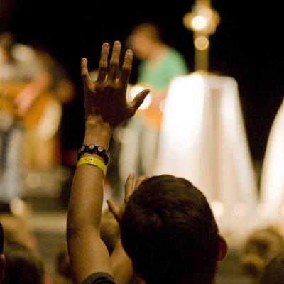 A young student raises his hand in prayer during adoration